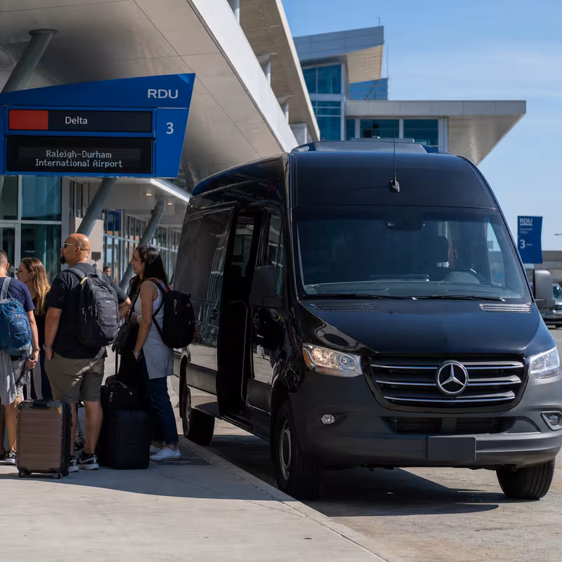 Group boarding a white charter bus for Airport Transportation transportation in Raleigh