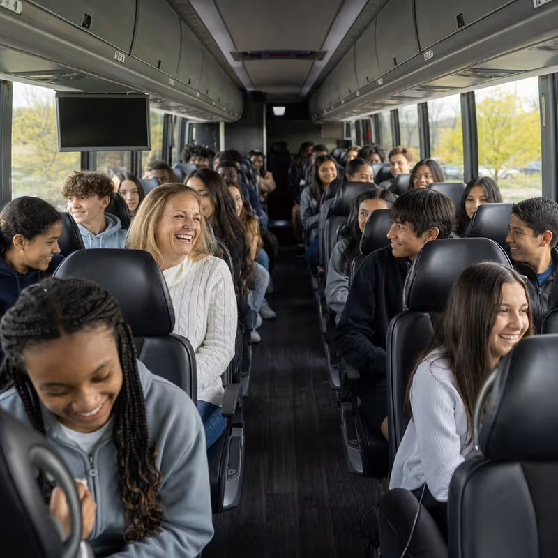 Group boarding a white charter bus for School Transportation transportation in Raleigh